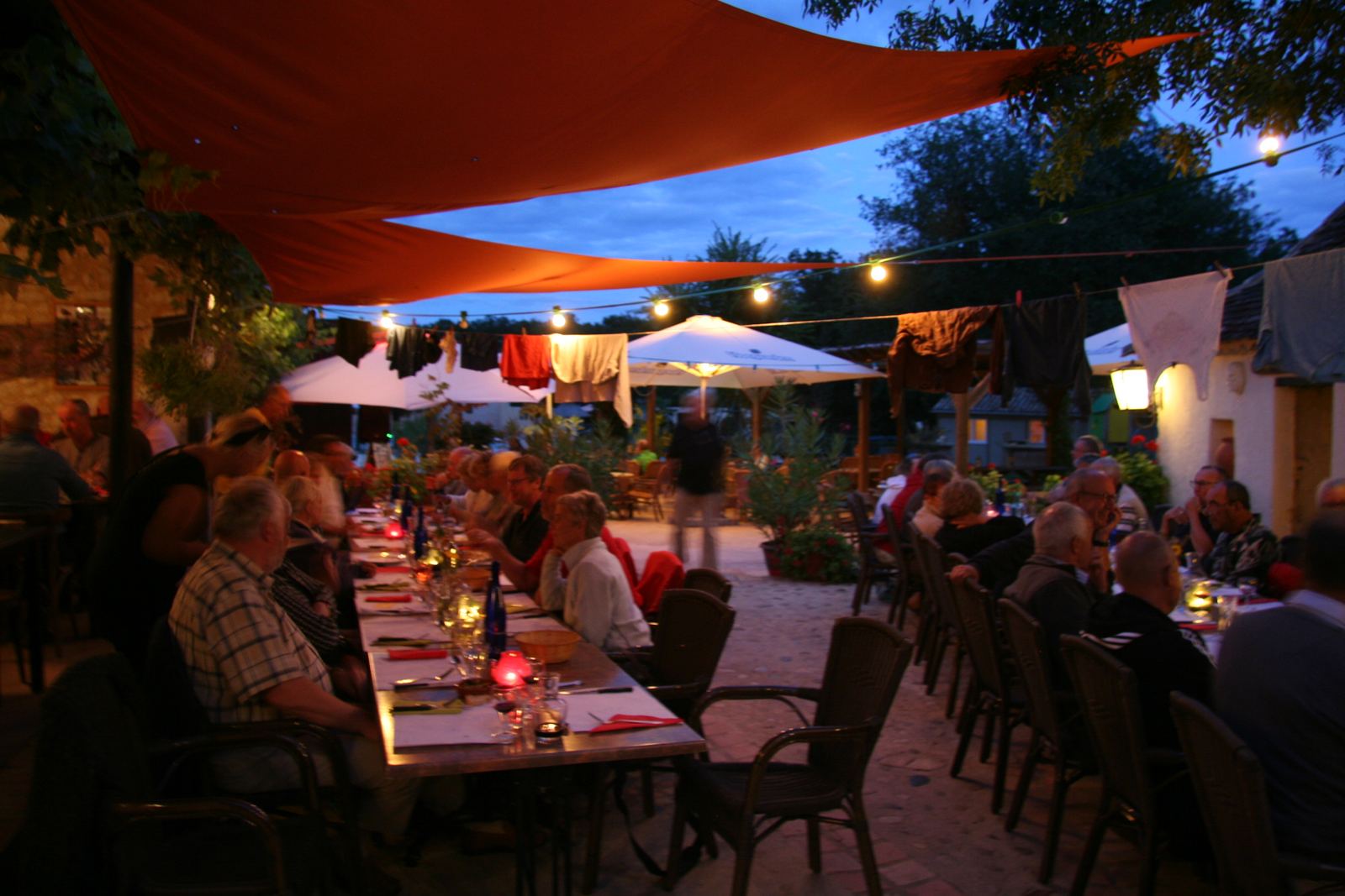 Gasten aan tafel op het terras in de schemering